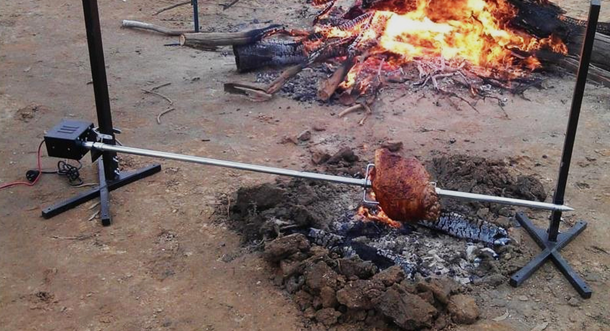 This image shows a portable camping spit with a big chunk of meat cooked on it. 
